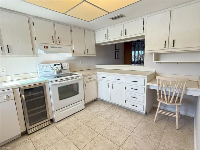 Kitchen featuring wine cooler, light tile patterned floors, and white appliances