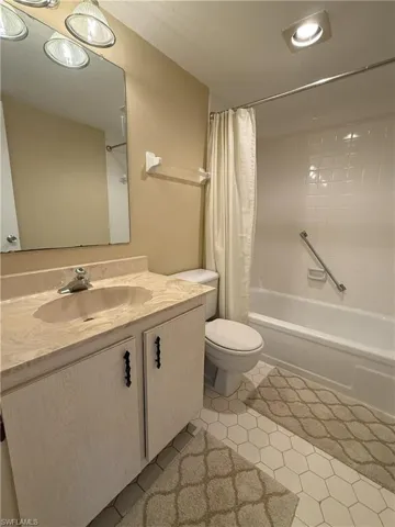Full bathroom with tile patterned floors, vanity, toilet, and shower / tub combo