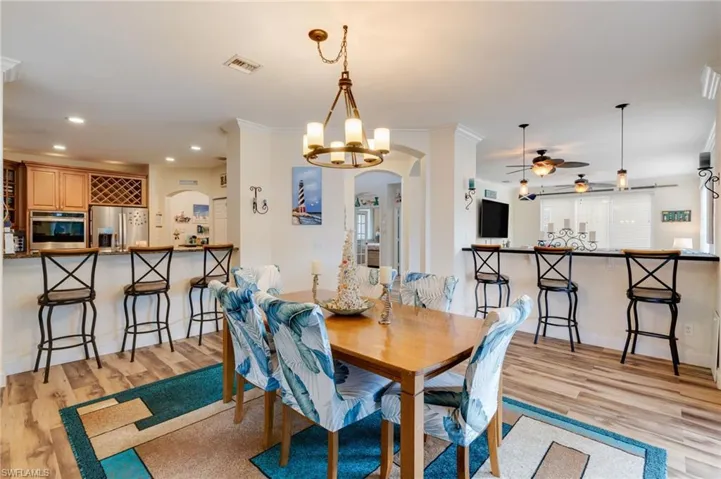 Dining room featuring arched walkways, a chandelier, light wood-type flooring, a ceiling fan, and recessed lighting