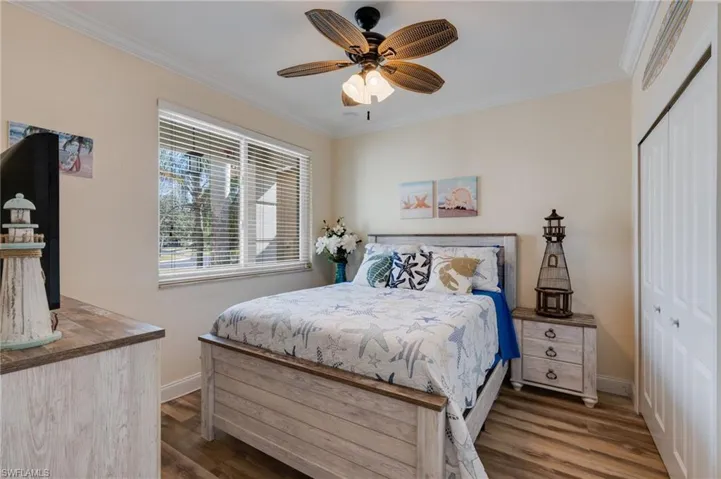 Bedroom featuring ornamental molding, a closet, dark wood-style floors, and ceiling fan