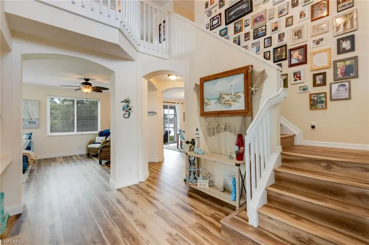 Stairs with a high ceiling, arched walkways, wood finished floors, and ceiling fan