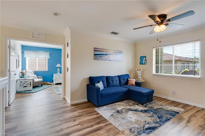Living room with crown molding, wood finished floors, and a ceiling fan