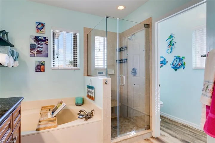Bathroom with vanity, a shower stall, a garden tub, and wood finished floors