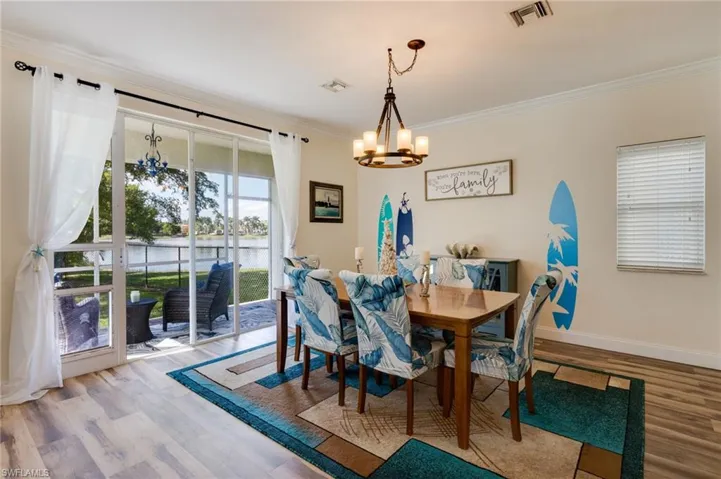 Dining space featuring a water view, crown molding, light wood-type flooring, and a chandelier
