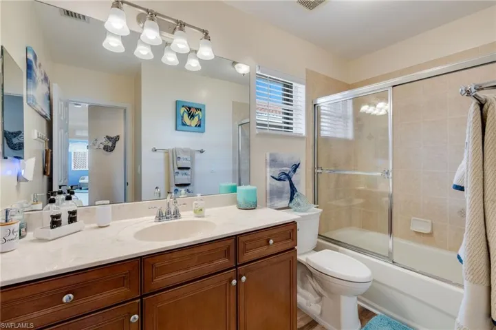 Full bath featuring vanity and shower / bath combination with glass door