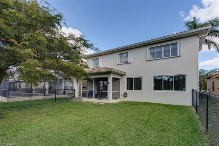 Rear view of property with a fenced backyard, a sunroom, and stucco siding