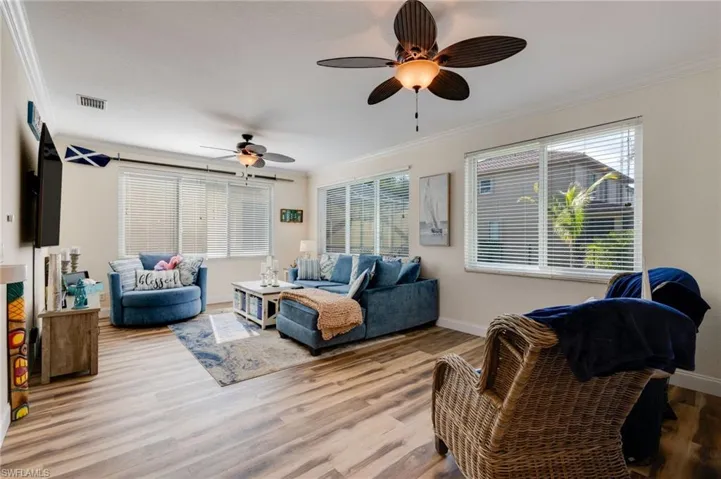 Living area with crown molding, wood finished floors, and ceiling fan