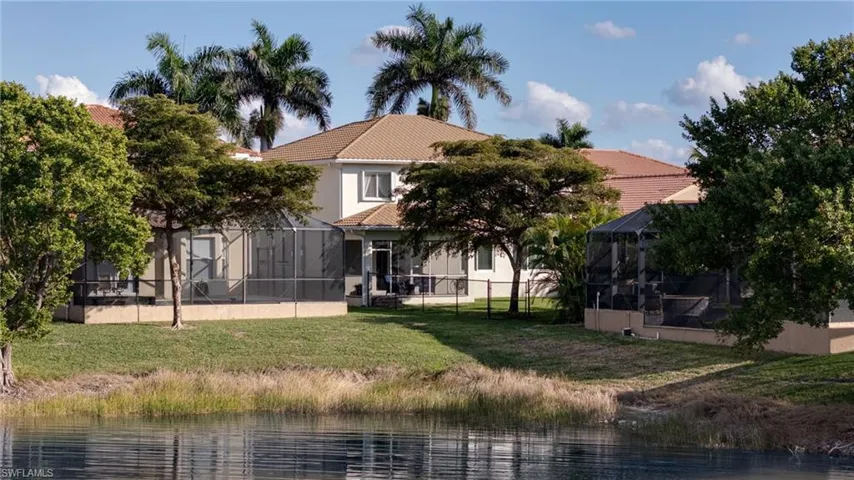 Rear view of house with a water view, a sunroom, a lanai, and a tiled roof