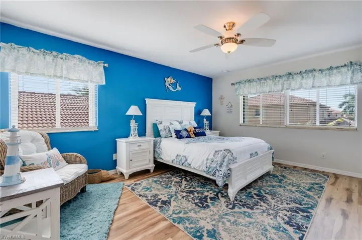 Bedroom with wood finished floors, multiple windows, and ceiling fan