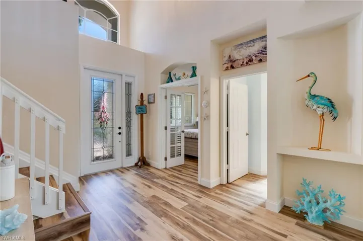 Entryway featuring plenty of natural light, a towering ceiling, light wood finished floors, and stairway