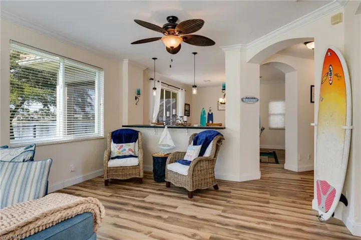 Sitting room featuring arched walkways, light wood finished floors, crown molding, plenty of natural light, and a ceiling fan