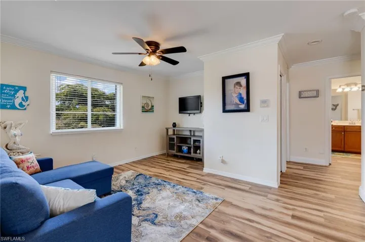 Living room with light wood-style flooring, ornamental molding, and a ceiling fan