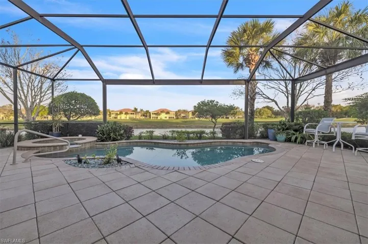 Screened-in patio featuring a paver deck, integrated spa, free-form pool, and water-facing scenery