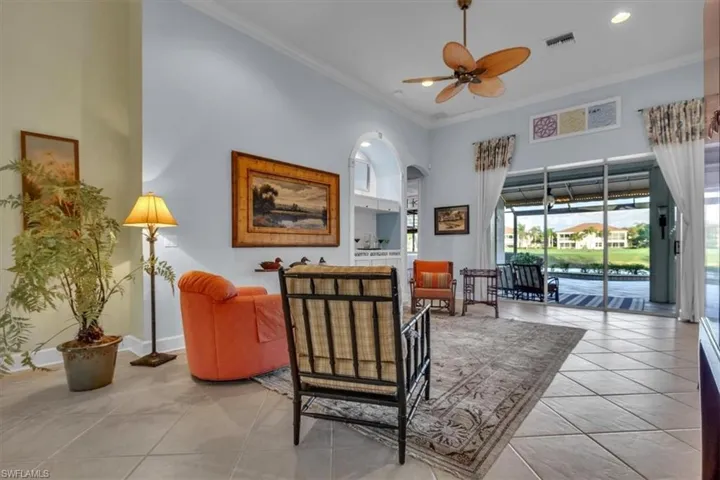High-ceiling living area featuring large-format diagonal floor tiling, recessed lighting, a ceiling fan with integrated light, and an arched built-in niche