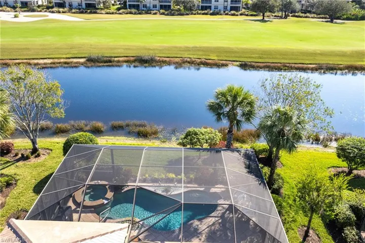 Screen-enclosed pool and spa featuring paver decking, situated on a lot bordering a lake and golf course