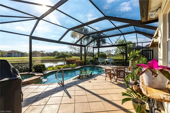 Screen-enclosed patio featuring a swimming pool, integrated spa, tile flooring, and metal frame structure