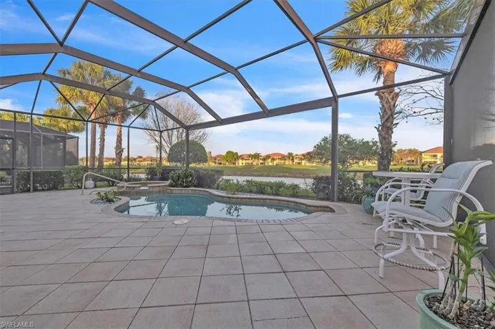 Screened-in patio featuring a tiled deck, built-in swimming pool, elevated spa, and water backdrop