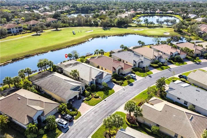 Aerial perspective of a residential property featuring a tiled roof, paver driveway, and a screened rear lanai, positioned on a waterfront lot with golf course frontage