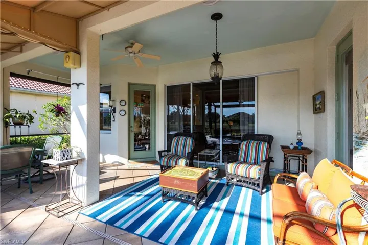Covered outdoor patio featuring light-toned tile flooring, a ceiling fan, a pendant light fixture, and a screened enclosure