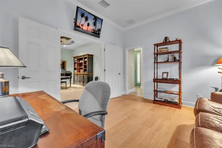 Room featuring wood-finish flooring, crown molding, and double door entry