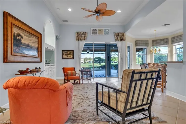 High ceilings featuring a paddle-style ceiling fan, built-in shelving with an arched decorative frame, large sliding glass doors, and tile flooring throughout