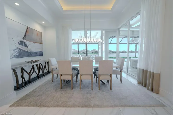 Dining area with a tray ceiling, an inviting chandelier, and a water view