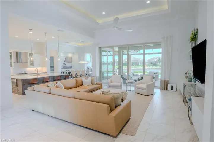 Living room with a raised ceiling, ceiling fan, sink, and a towering ceiling