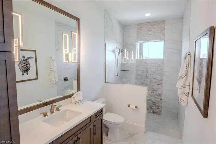Bathroom with tiled shower, vanity, and toilet