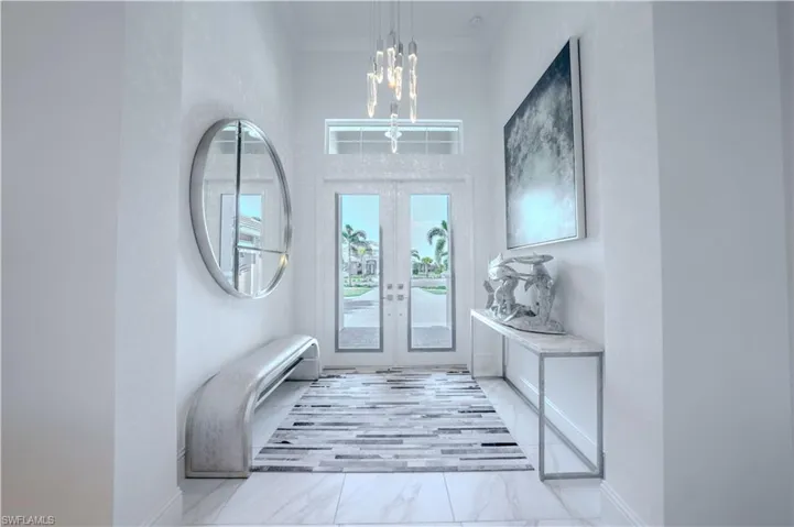 Entryway with french doors, an inviting chandelier, and ornamental molding
