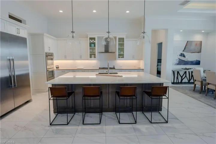 Kitchen with pendant lighting, white cabinetry, an island with sink, and appliances with stainless steel finishes