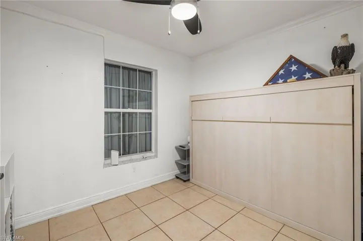 Unfurnished bedroom with light tile patterned flooring, a closet, ornamental molding, and ceiling fan