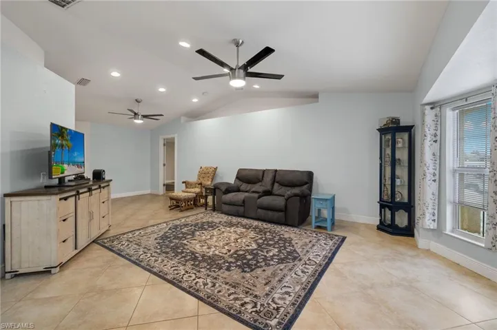 Tiled living room featuring a healthy amount of sunlight, ceiling fan, and lofted ceiling