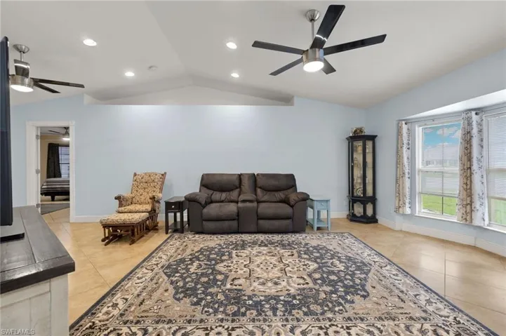 Tiled living room featuring vaulted ceiling and ceiling fan
