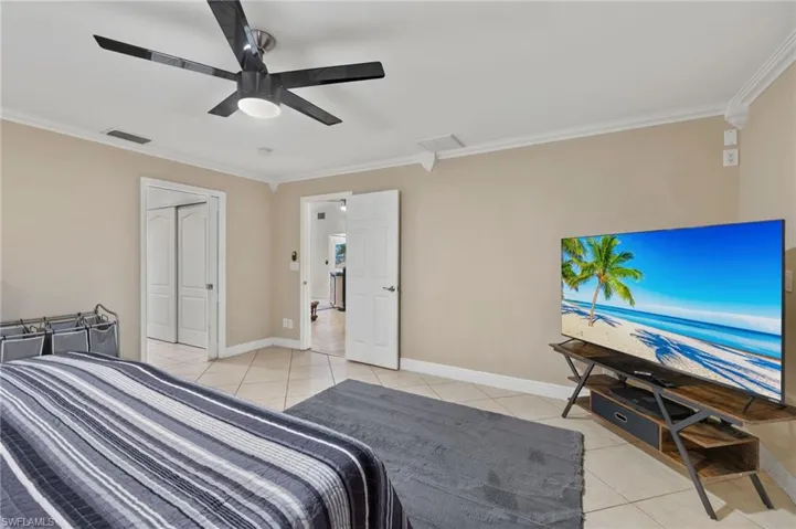 Bedroom featuring a closet, crown molding, ceiling fan, and light tile patterned floors