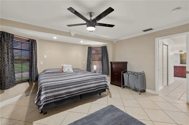 Bedroom featuring light tile patterned flooring, ornamental molding, and ceiling fan