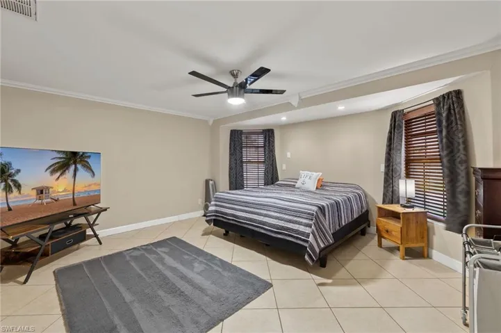 Tiled bedroom with crown molding and ceiling fan
