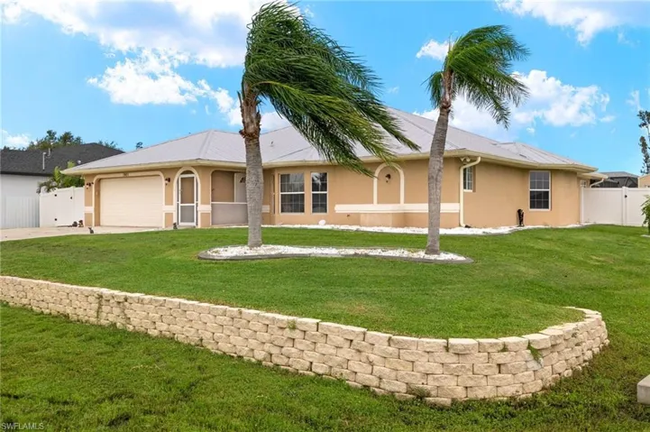 Rear view of property featuring a garage and a lawn