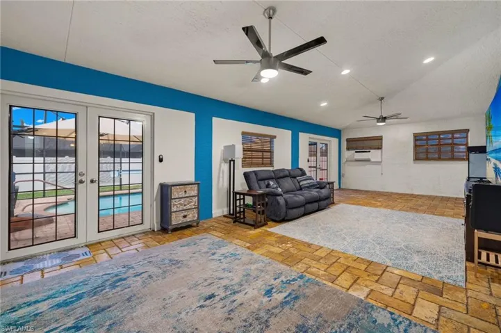 Living room featuring a textured ceiling, lofted ceiling, french doors, and ceiling fan