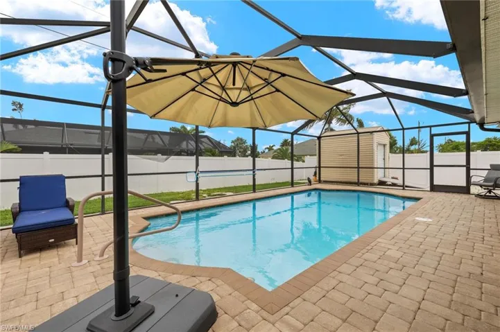 View of swimming pool featuring a patio area, a shed, and glass enclosure