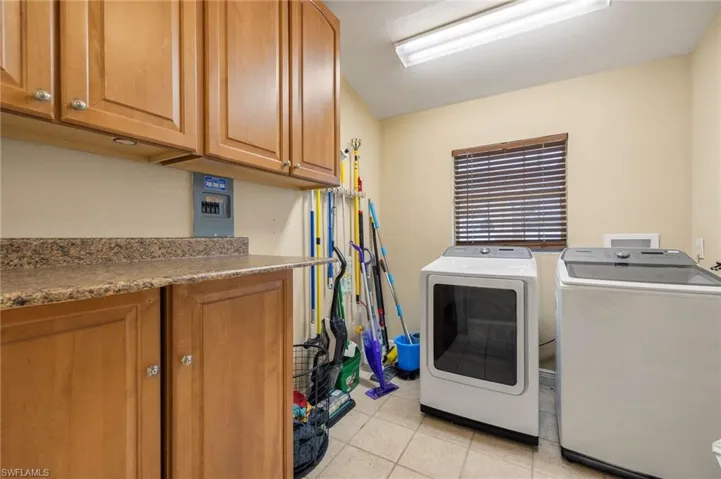 Washroom featuring cabinets, washing machine and clothes dryer, and light tile patterned floors
