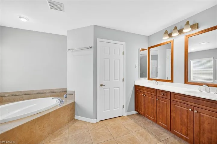 Full bath with a garden tub, double vanity, and tile patterned flooring