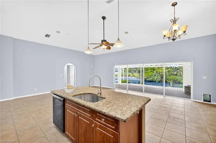 Kitchen with open floor plan, light tile patterned floors, arched walkways, pendant lighting, and dishwasher