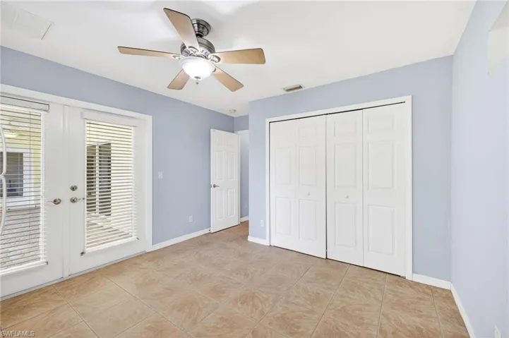 Unfurnished bedroom with access to exterior, light tile patterned floors, french doors, ceiling fan, and a closet