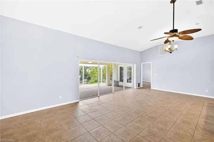 Tiled spare room with ceiling fan, french doors, and high vaulted ceiling