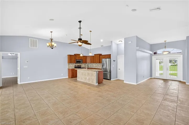 Kitchen with open floor plan, decorative backsplash, french doors, light tile patterned floors, and high vaulted ceiling