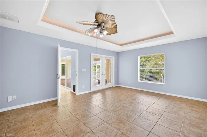 Tiled spare room featuring a tray ceiling and ceiling fan