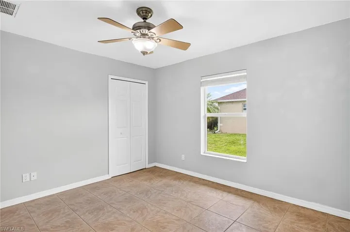 Unfurnished bedroom featuring light tile patterned floors, a closet, and a ceiling fan