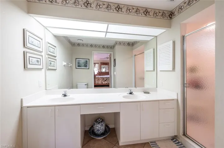 Ensuite bathroom featuring a stall shower, a sink, toilet, and double vanity