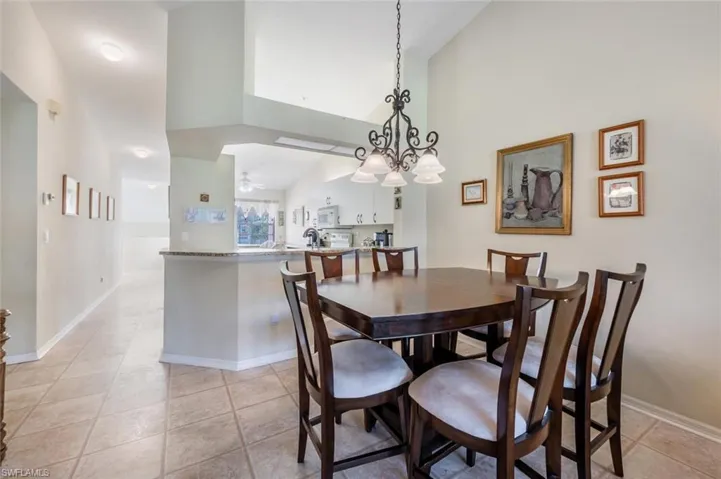 Dining space with light tile patterned floors, ceiling fan, high vaulted ceiling, and baseboards