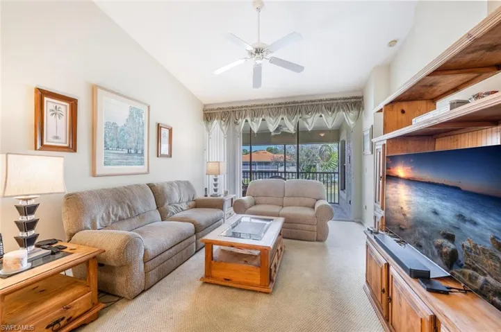 Living room featuring light carpet, vaulted ceiling, and a ceiling fan